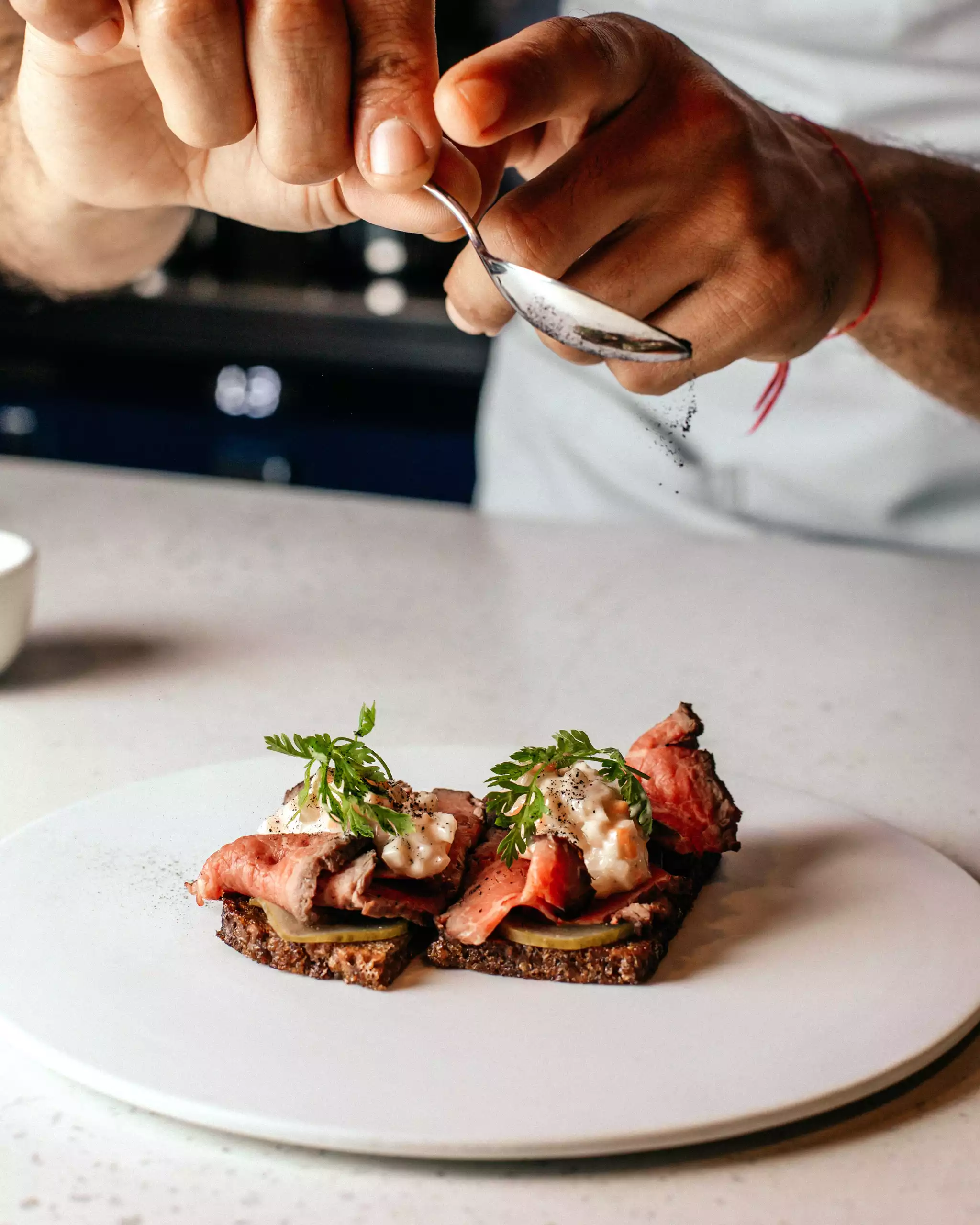 Fein angerichtetes Gourmet-Menü mit Roastbeef auf Brot, garniert mit Kräutern und Sauce, Maison Talmühle Resort Schwarzwald