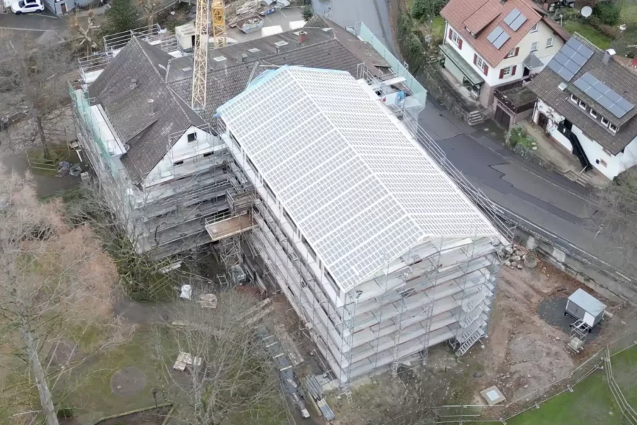 Luftaufnahme einer Baustelle mit eingerüstetem Gebäude im Schwarzwald, Baufortschritt Maison Talmühle Dezember 2024