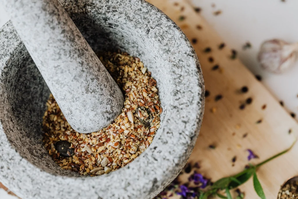 Mörser aus Granit mit gemahlenen Gewürzen und Kräutern auf Holzbrett im Boutique Resort Maison Talmühle Schwarzwald Spa