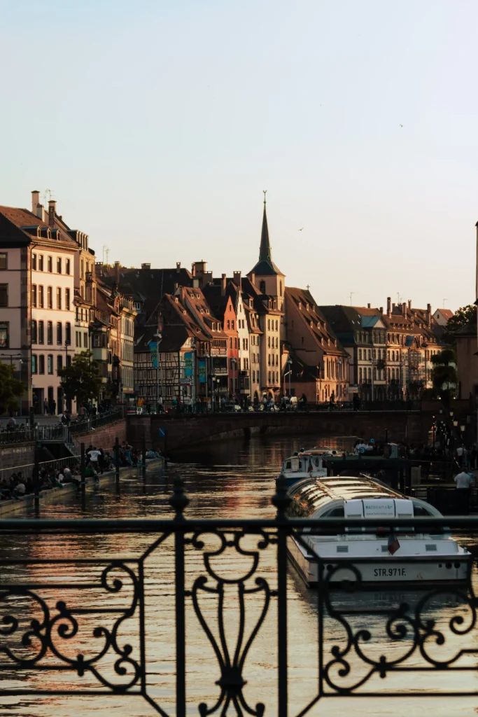 Blick auf die Altstadt von Straßburg mit Fachwerkhäusern, Kirche und Boot auf dem Fluss bei Sonnenuntergang
