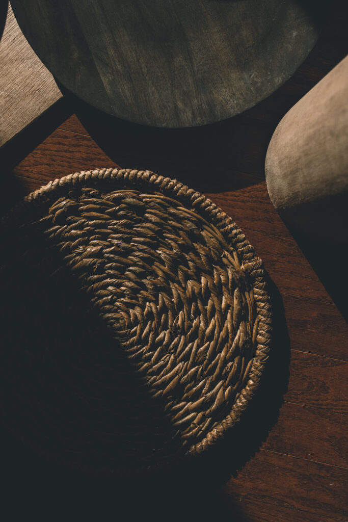 Runder geflochtener Untersetzer aus Naturmaterial auf Holzboden neben Möbelstücken in Boutique Resort Maison Talmühle