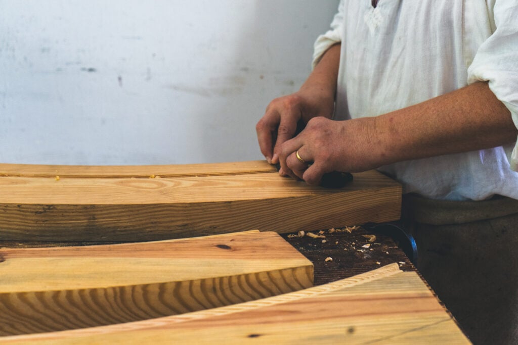 Handwerker in Werkstatt bearbeitet Holz mit Hobel auf Werkbank im Schwarzwald Boutique Resort Maison Talmühle