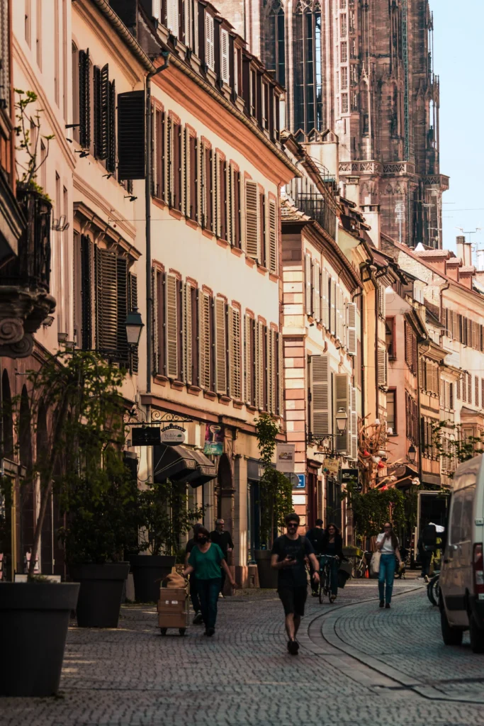 Belebte Kopfsteinpflasterstraße mit historischen Gebäuden und Blick auf den Straßburger Münster im Boutique-Resort-Stil